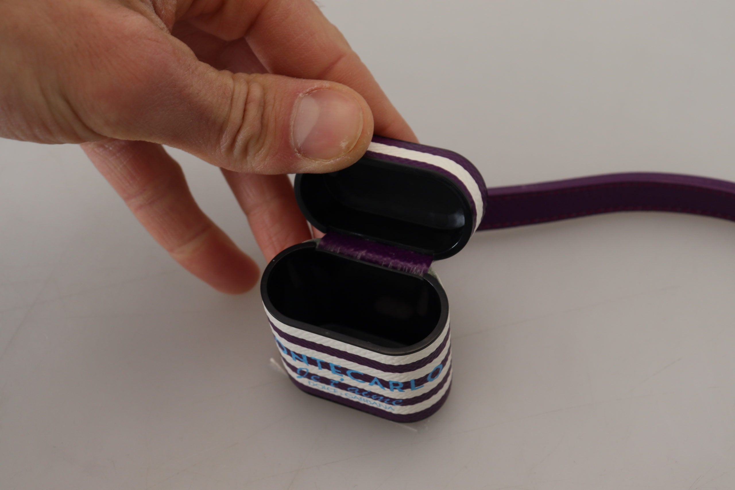 Fialový kožený řemínek s kovovým logem a zlatým pouzdrem na Airpods